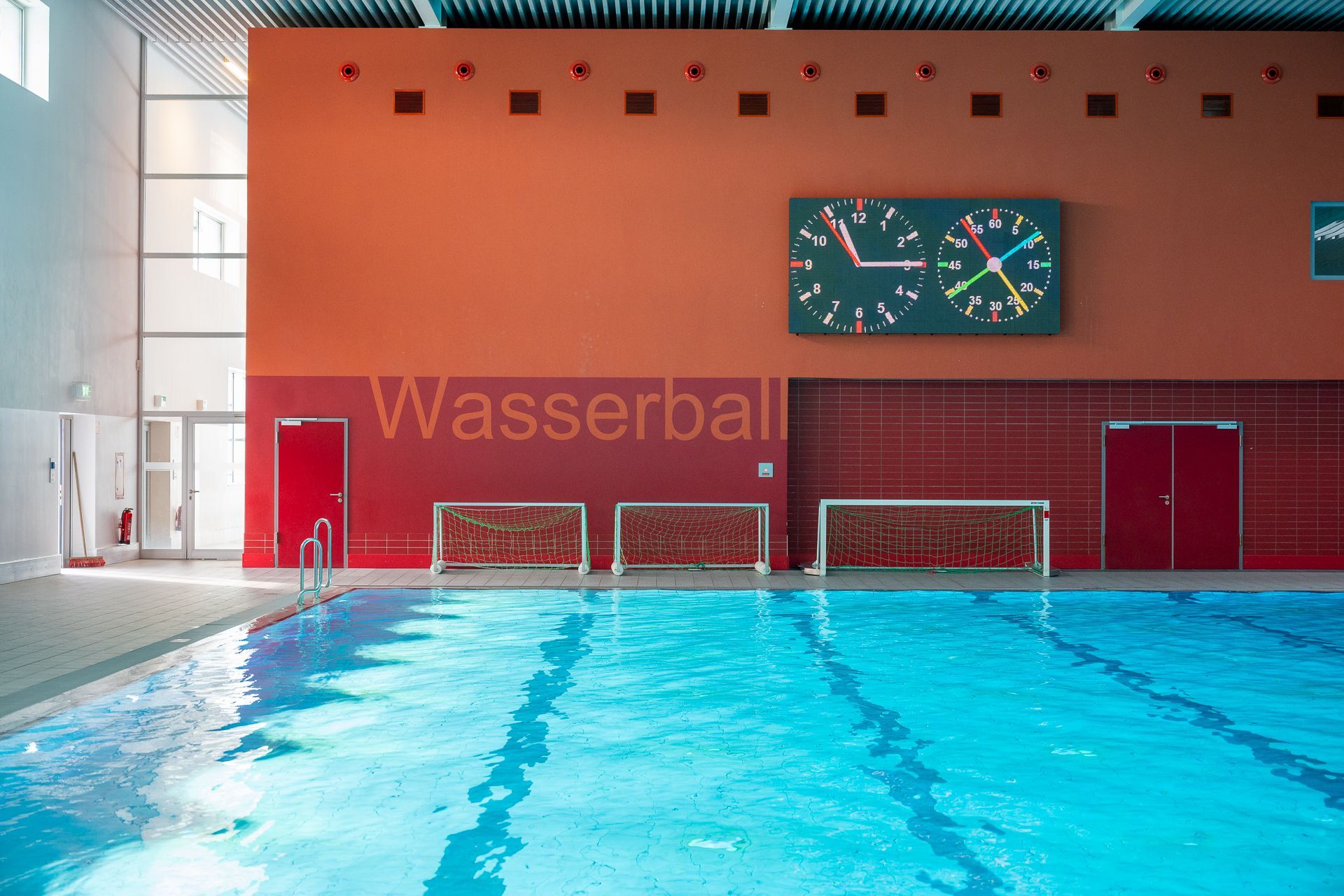 Hallenbad mit Wasserballtoren, Anzeigetafel und dem Schriftzug „Wasserball“ an der Wand.