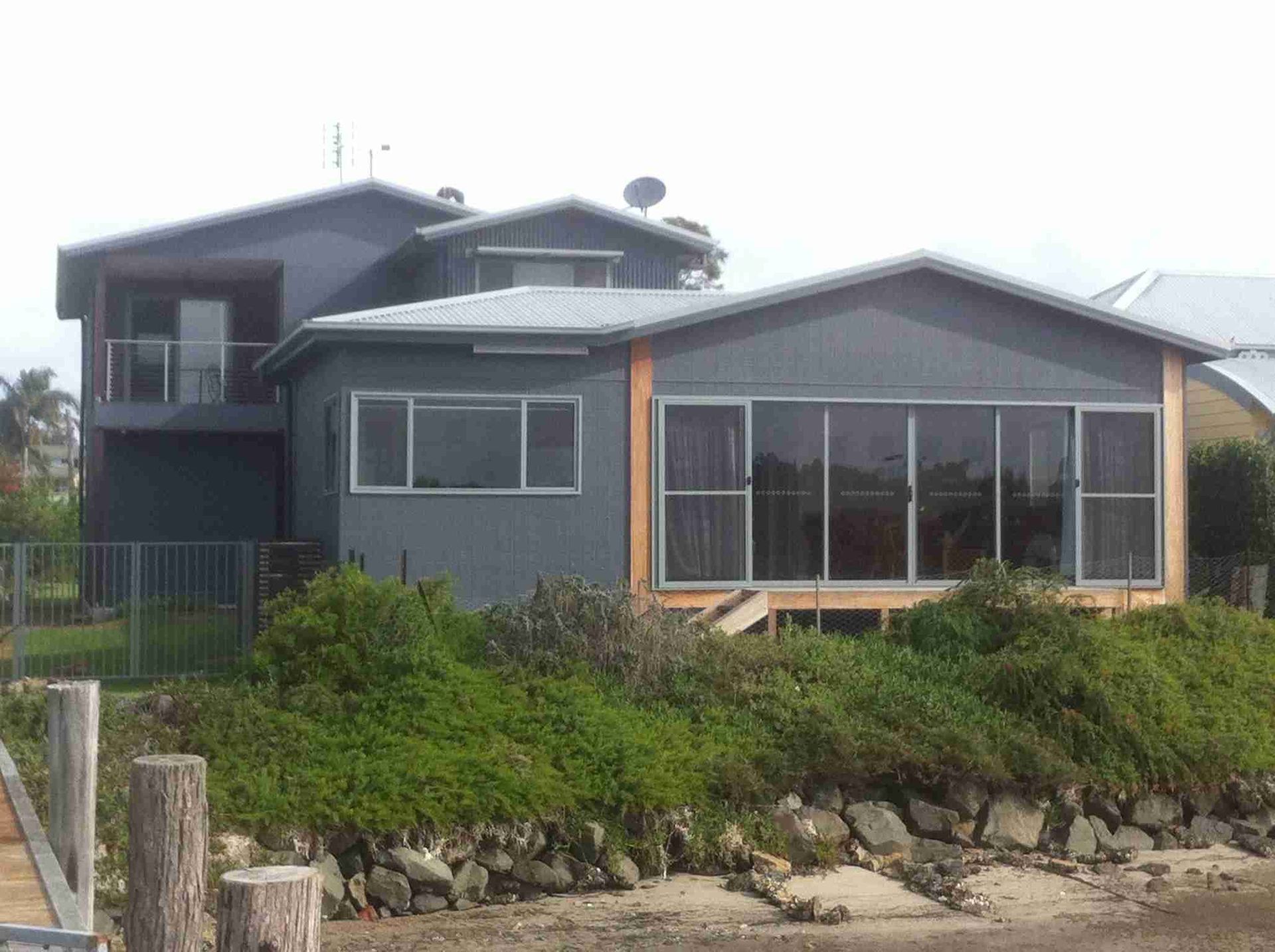 Gray house with large windows and a garden by the roadside