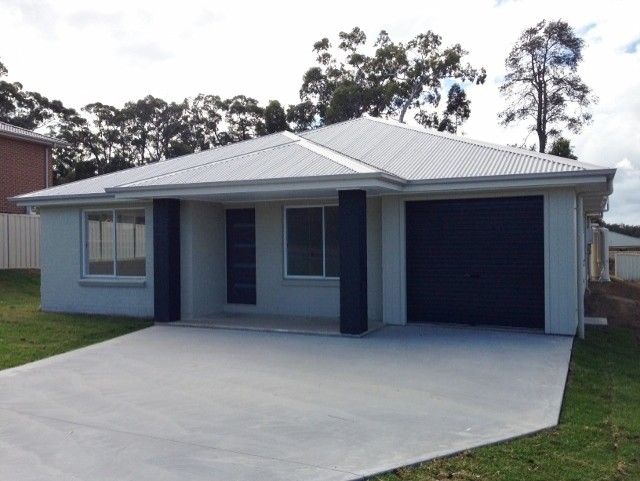 Single-story light-blue house with a gray roof, wide driveway, and attached garage.