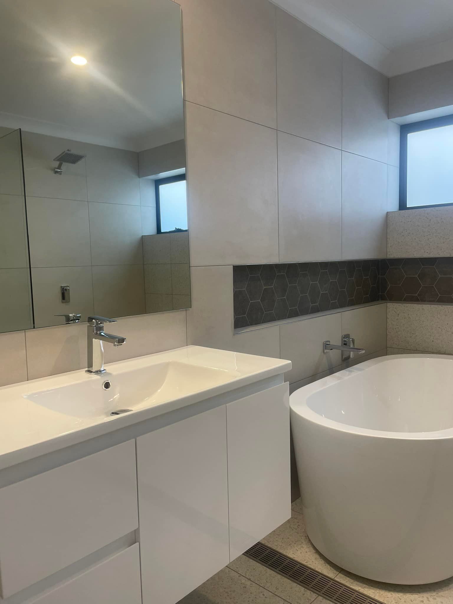 Modern bathroom with floating sink vanity, mirror, and freestanding oval bathtub.