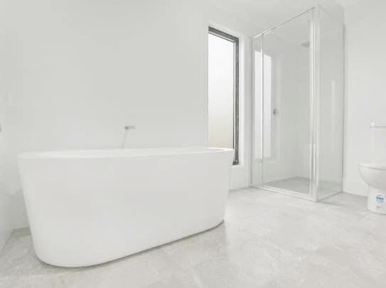 Minimal white bathroom with a freestanding tub, shower, and bright windows