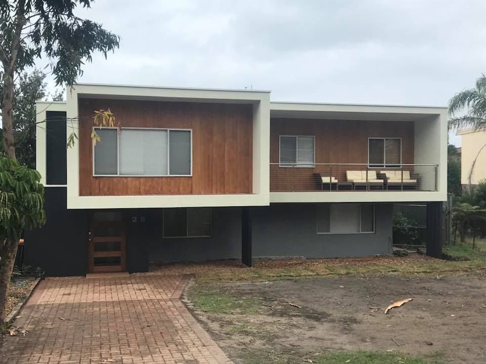 Modern two-story house with large windows, wood accents, and a brick driveway