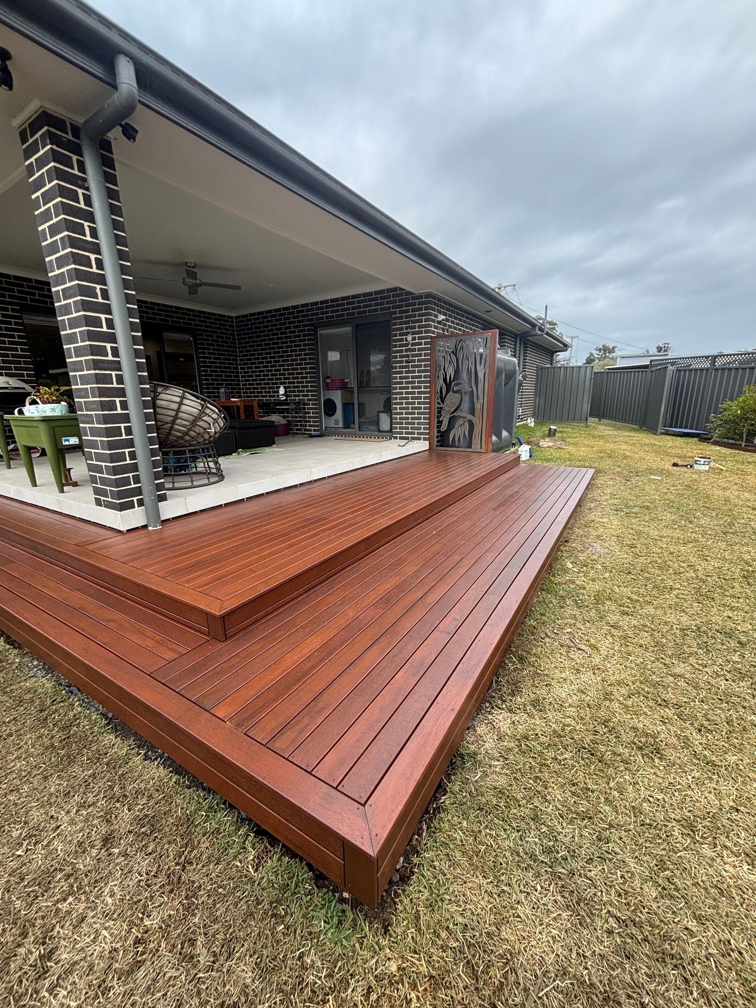 Wooden deck and ramp beside a modern house in a grassy backyard.