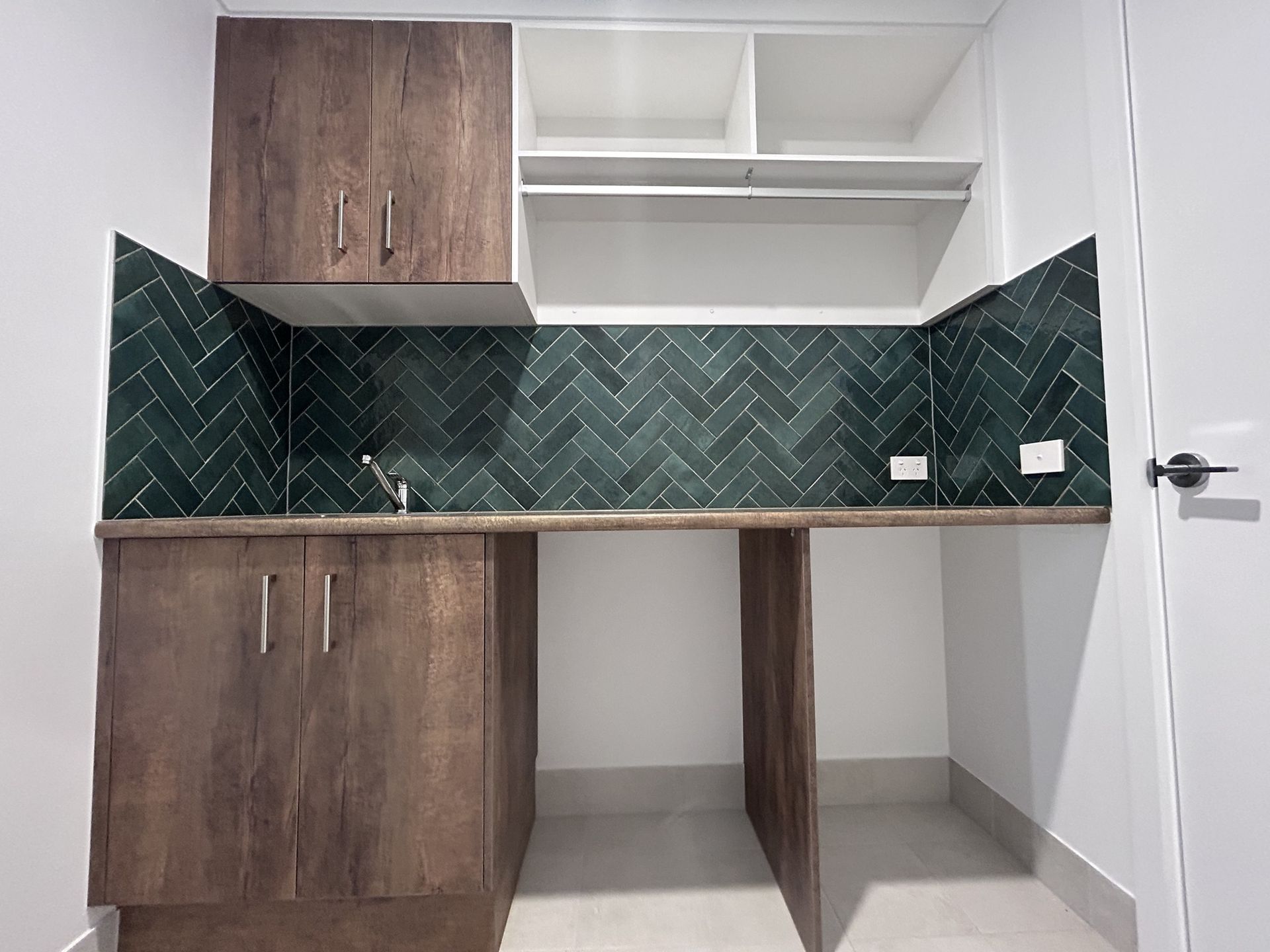 Laundry room with a washer, utility sink, and tall storage cabinet on tiled floor.