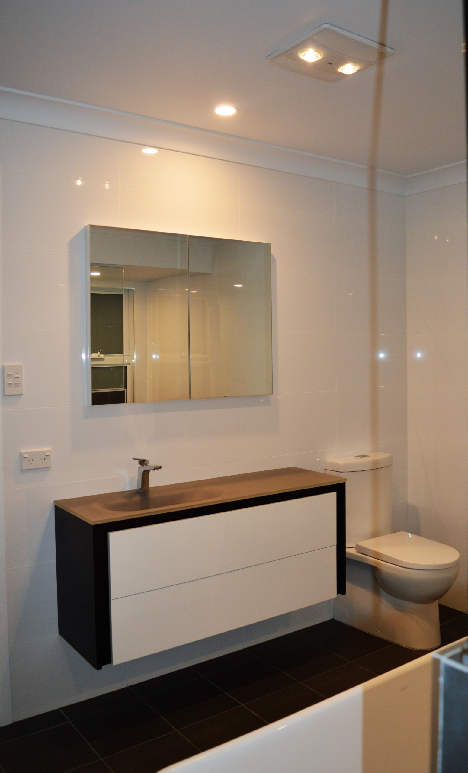 Modern bathroom with white walls, dark floor, wall mirror, sink vanity, and toilet