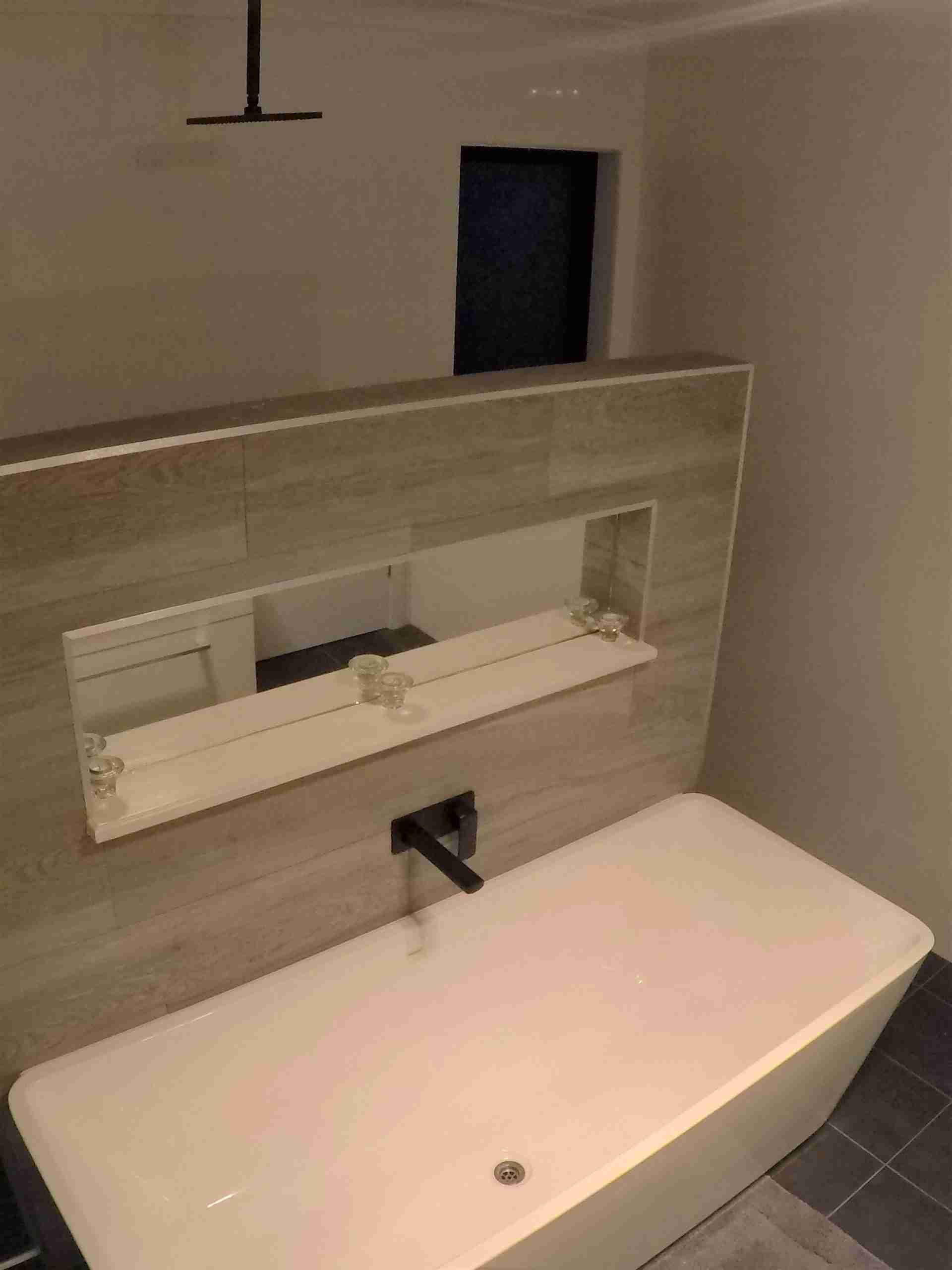 Modern bathroom sink and bathtub with mirror and dark tiled floor