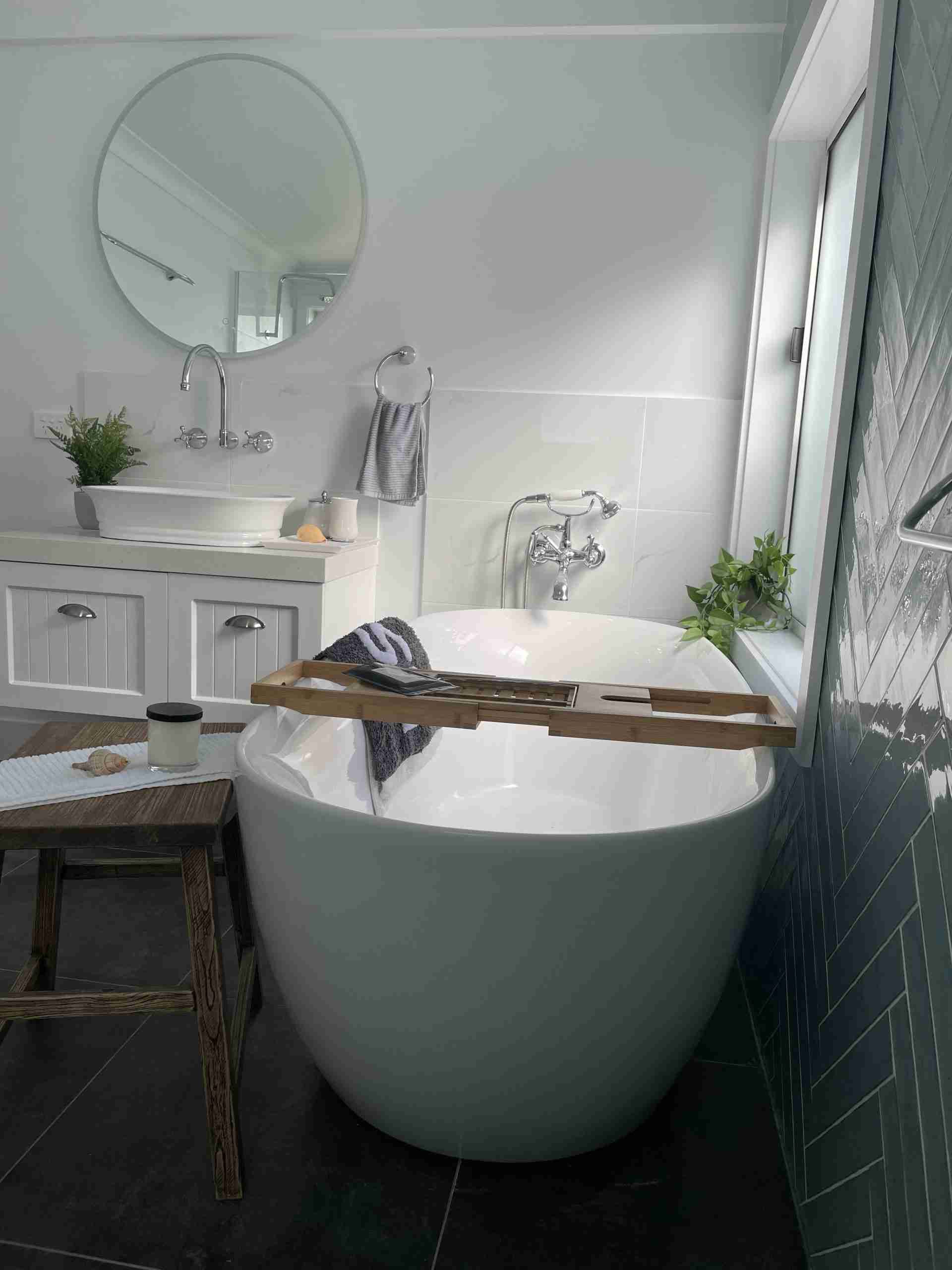 Modern bathroom with a freestanding tub, vanity, round mirror, and rain shower.