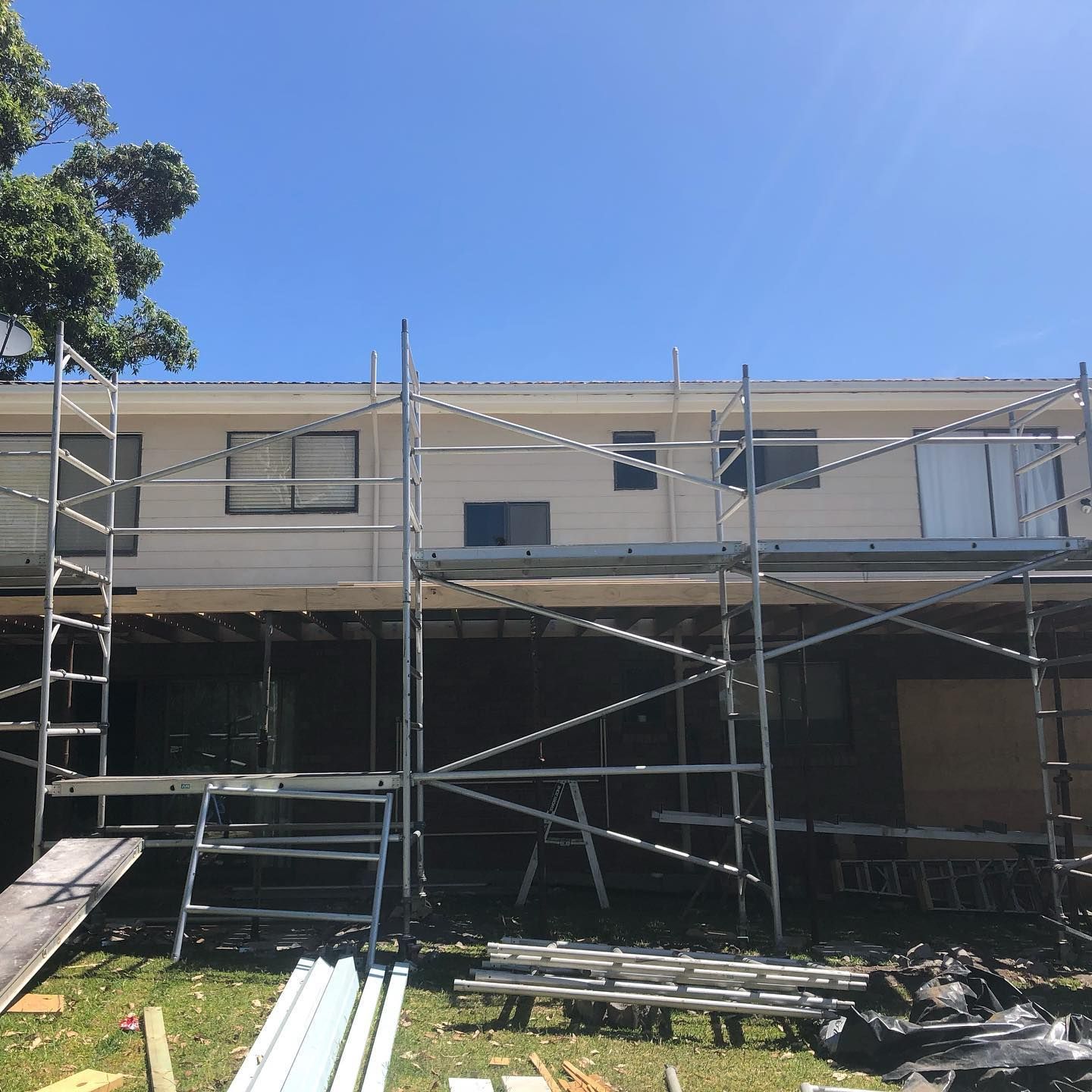 Scaffolding around a two-story house under renovation on a sunny day