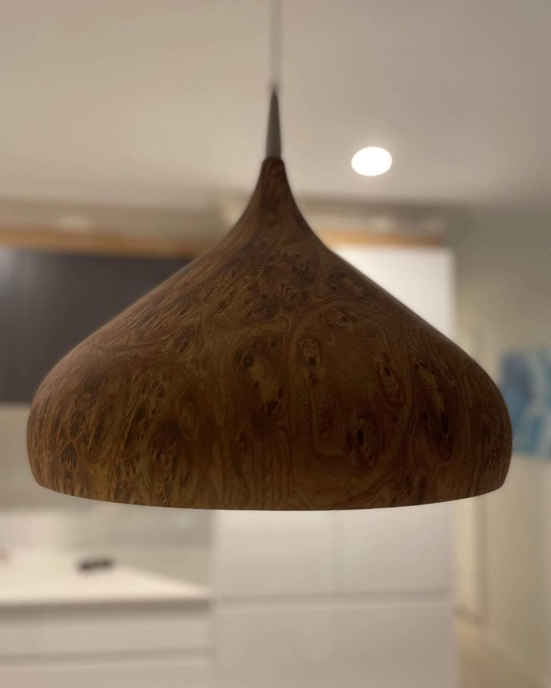 Teardrop-shaped wooden pendant lamp hanging in a modern kitchen