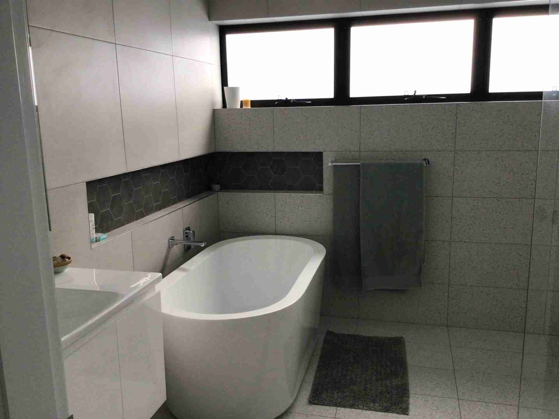 Modern bathroom with freestanding tub, shower, sink, and gray tile walls