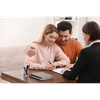 Couple signing documents with a counselor at a desk in a bright office
