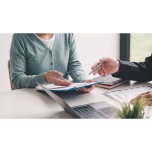 Two people reviewing documents at a desk with a laptop and pen in a bright office setting