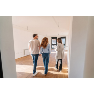 Three people walking through a bright, empty apartment with hardwood floors