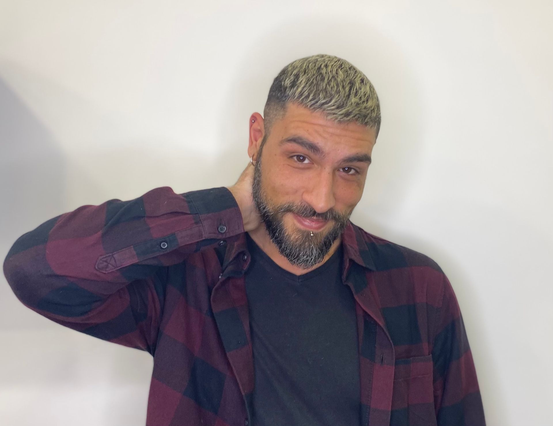Uomo con i capelli biondi corti e la barba, che posa davanti a uno sfondo bianco uniforme.
