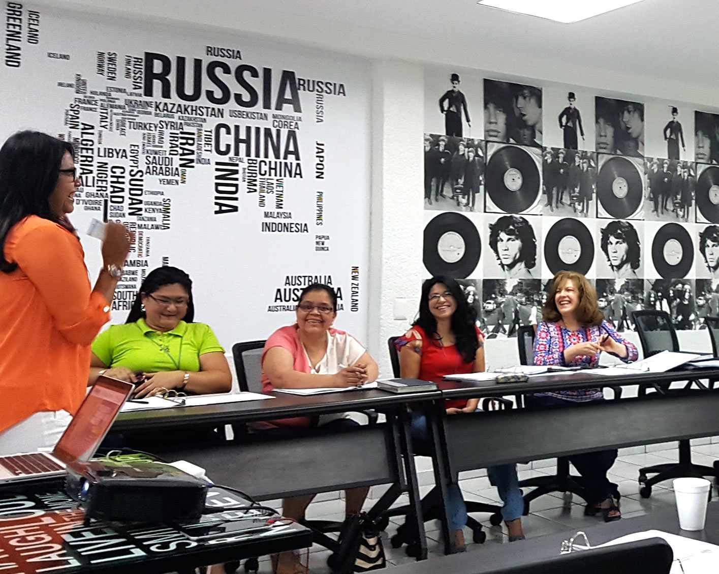 Debate en el aula con participantes sentados y un presentador de pie junto a una pared etiquetada como “Rusia”, “China” e “India”.
