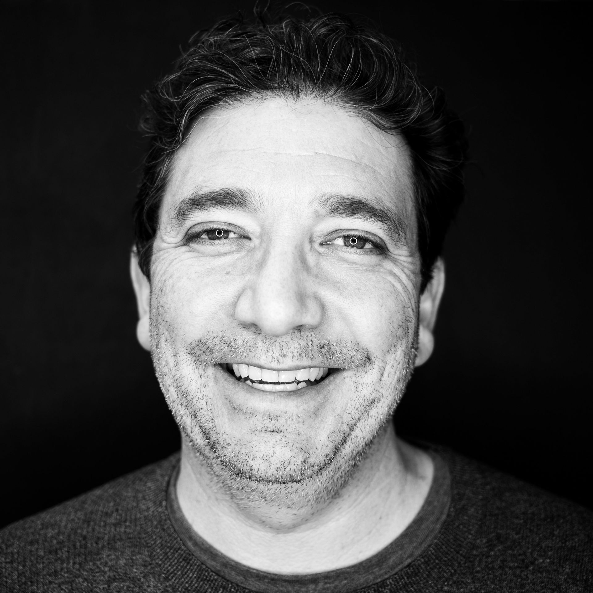 Smiling man with dark hair, looking at the camera.