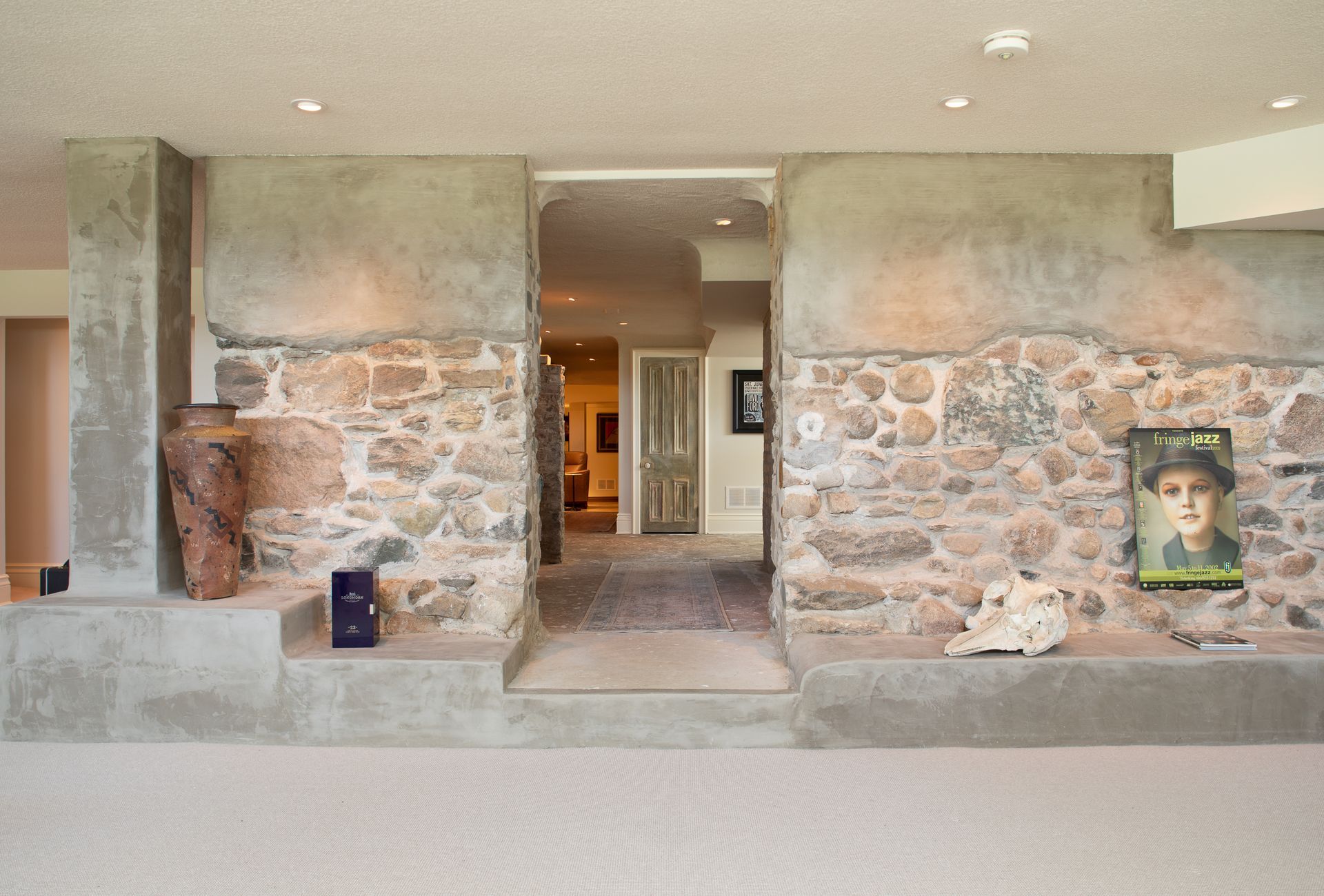 Stone and plaster interior doorway; tan walls and white carpet, artwork, and steps.