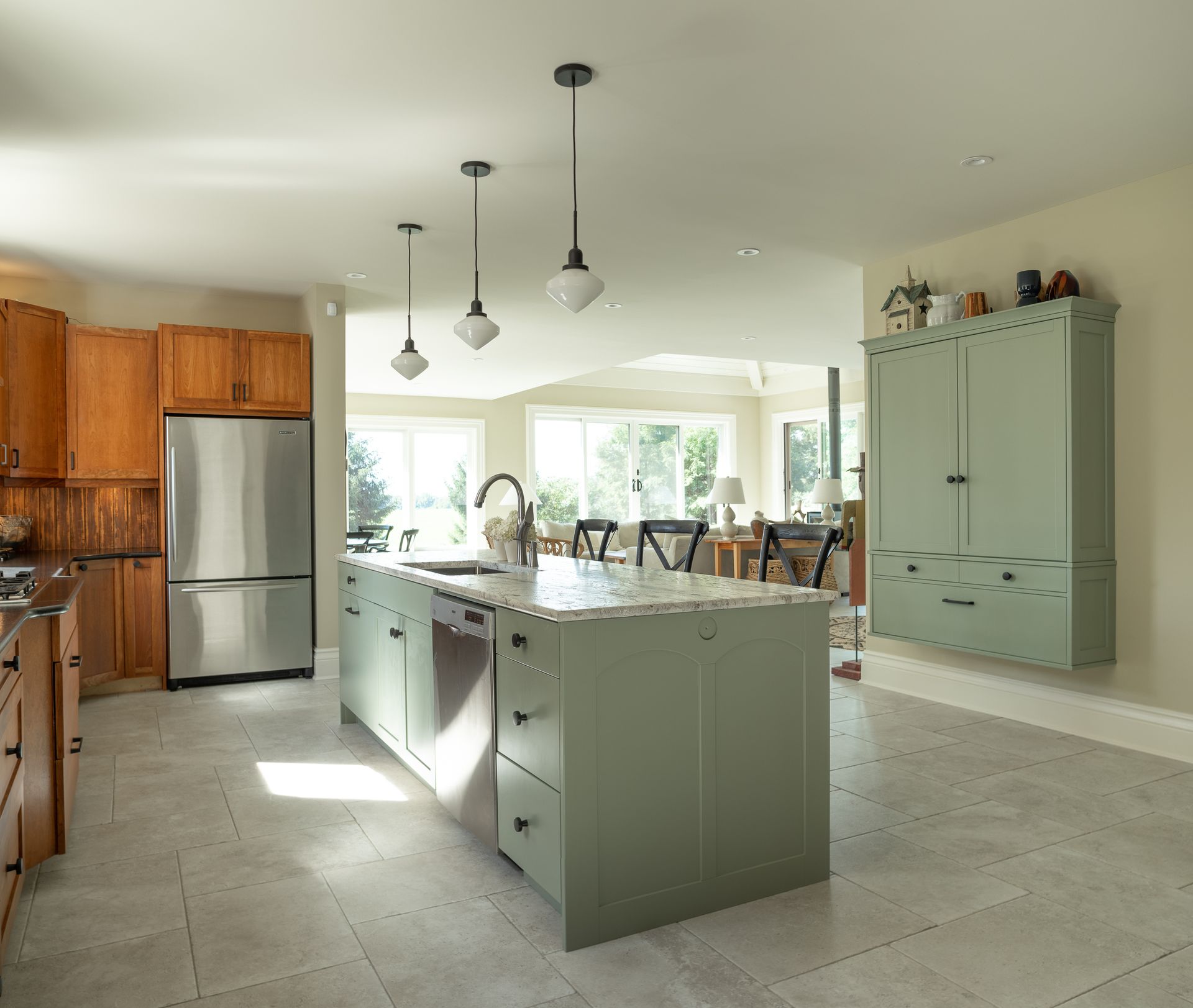 Kitchen with sage green island and cabinets, stainless steel appliances, and tile flooring.