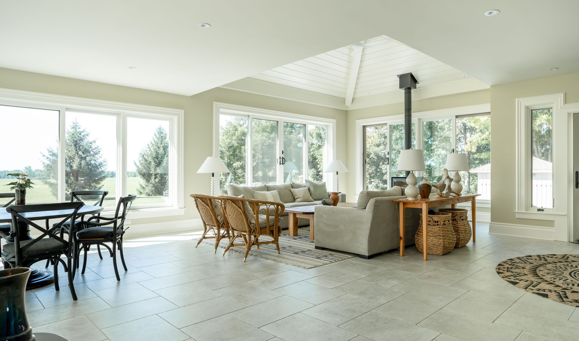 Bright, open living space with windows, seating area, dining table, and a ceiling fireplace.