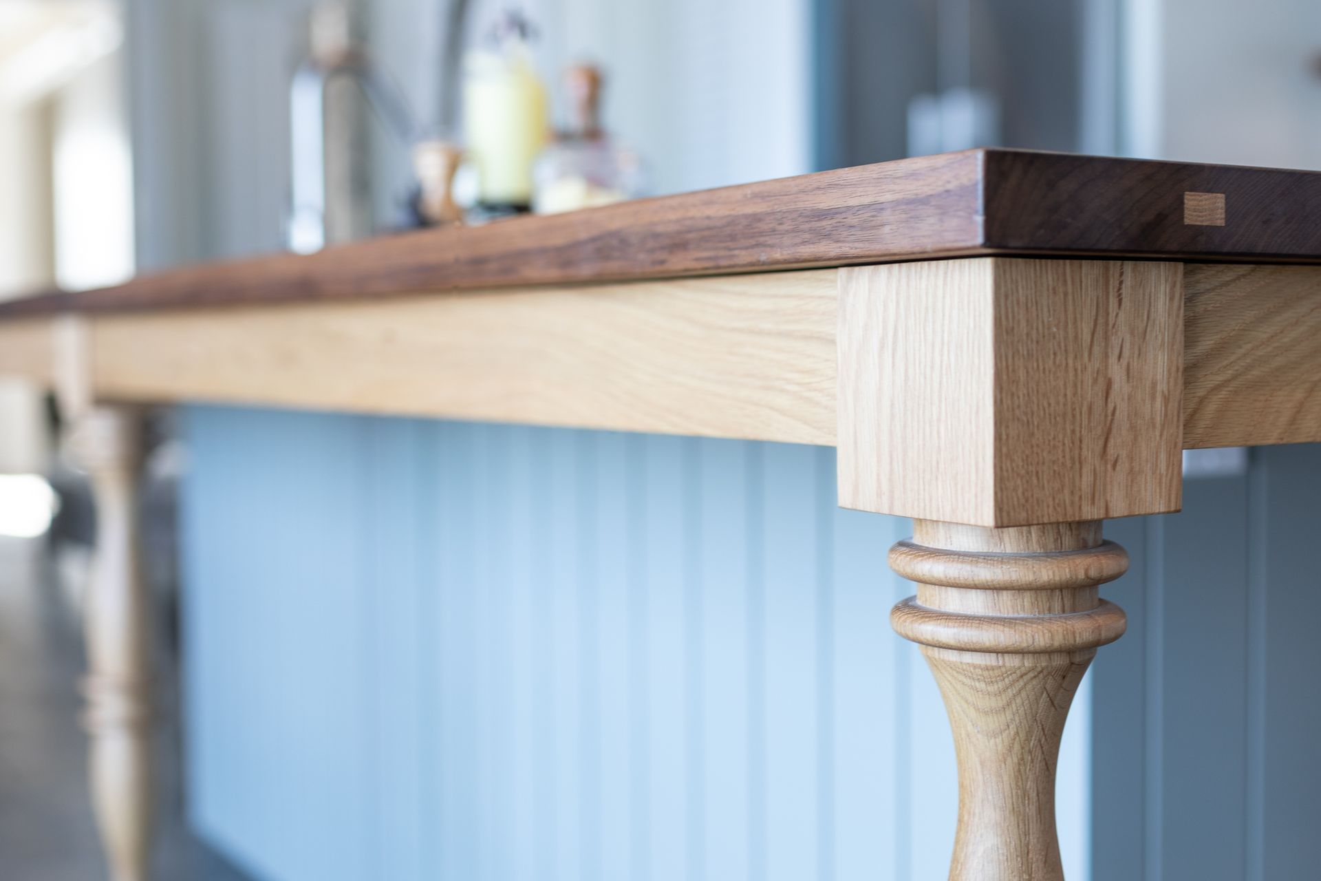 Close-up of a kitchen island with a light wooden base and a dark wooden countertop.