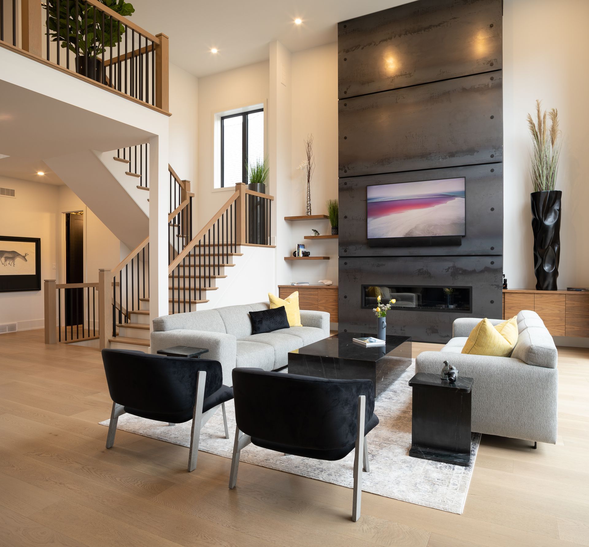 Modern living room with fireplace, gray sofa, and stairs.