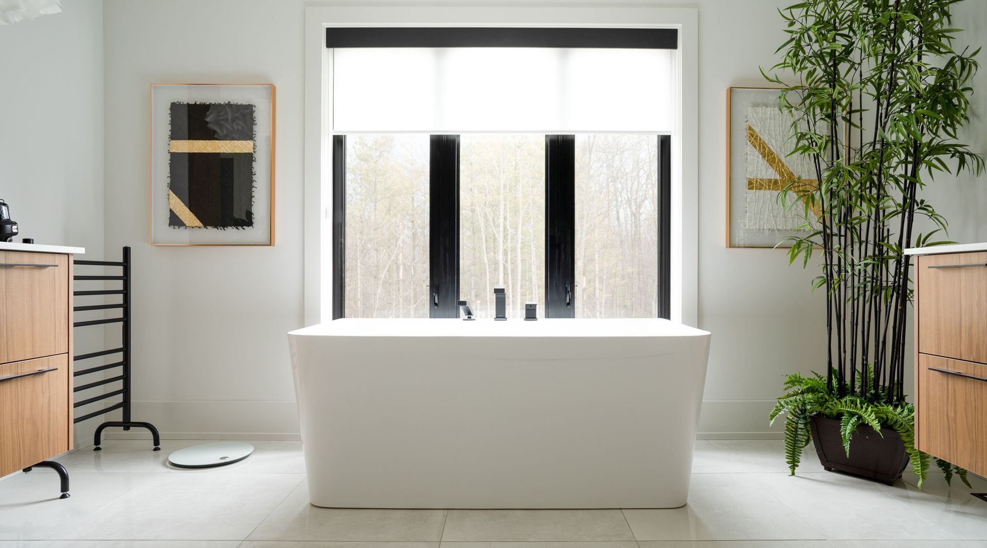 Modern white bathroom with a bathtub under a window. Bamboo plant on the right.