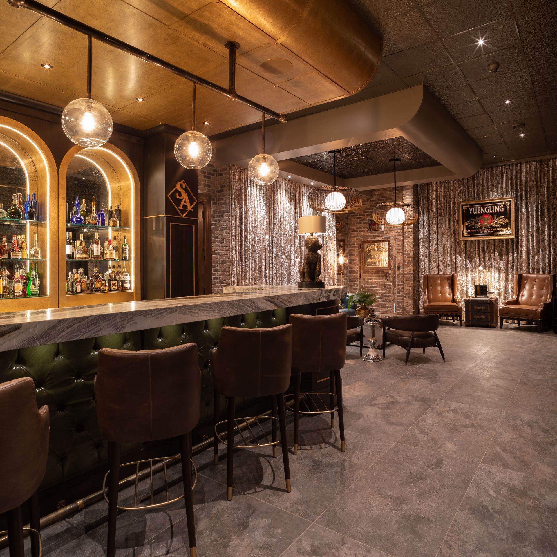 Stylish bar interior with a green marble countertop, brown stools, and decorative lighting.