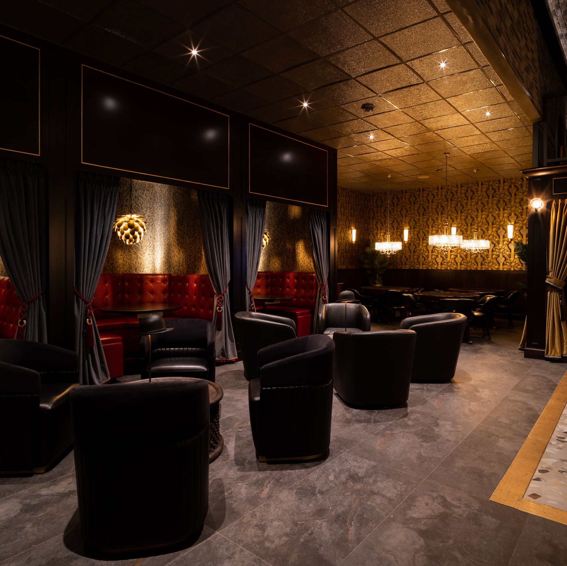 Luxurious dimly lit lounge with black leather chairs, dark curtains, and patterned walls.