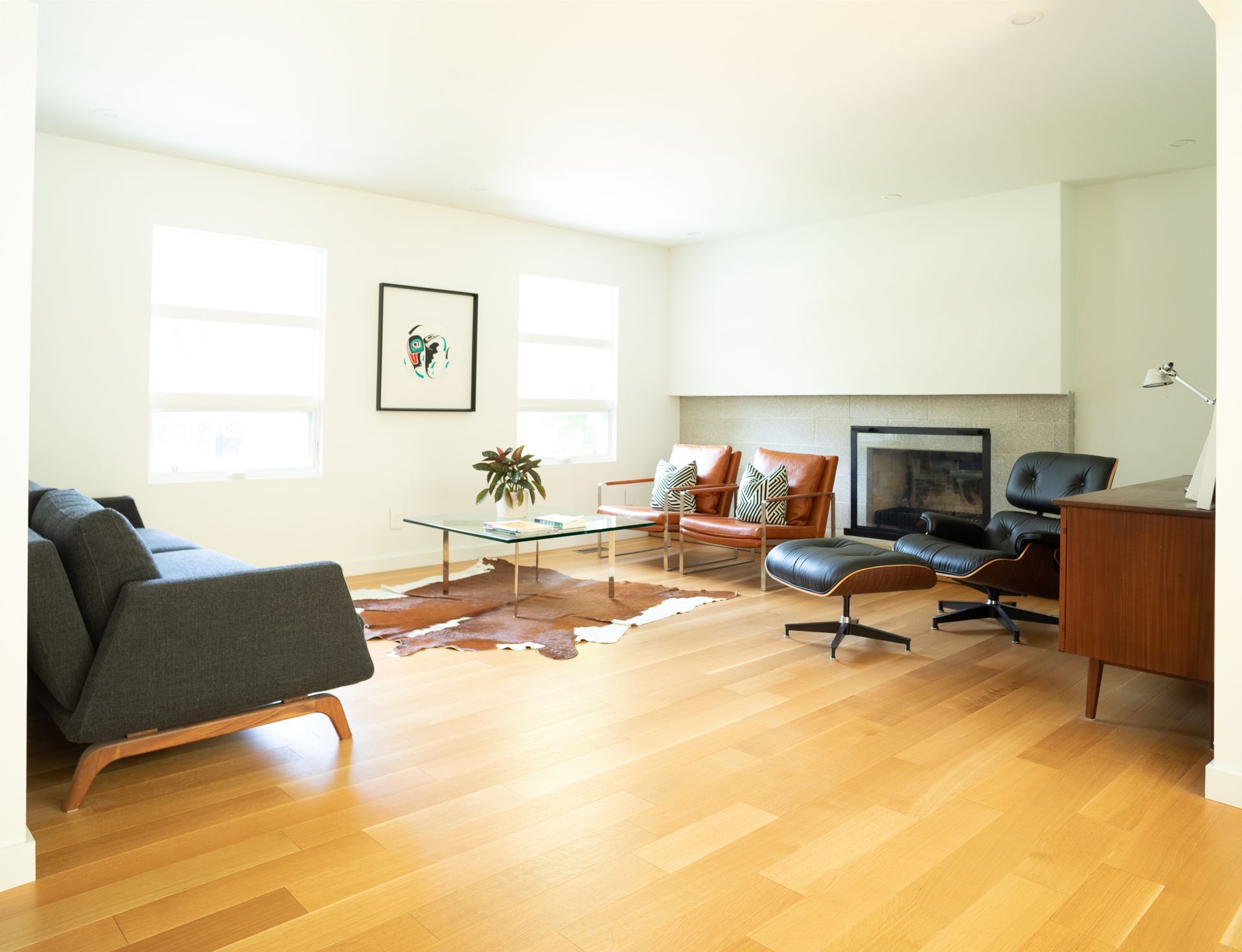 Living room with mid-century modern furniture, including a sofa, chairs, and a fireplace, on a wood floor.