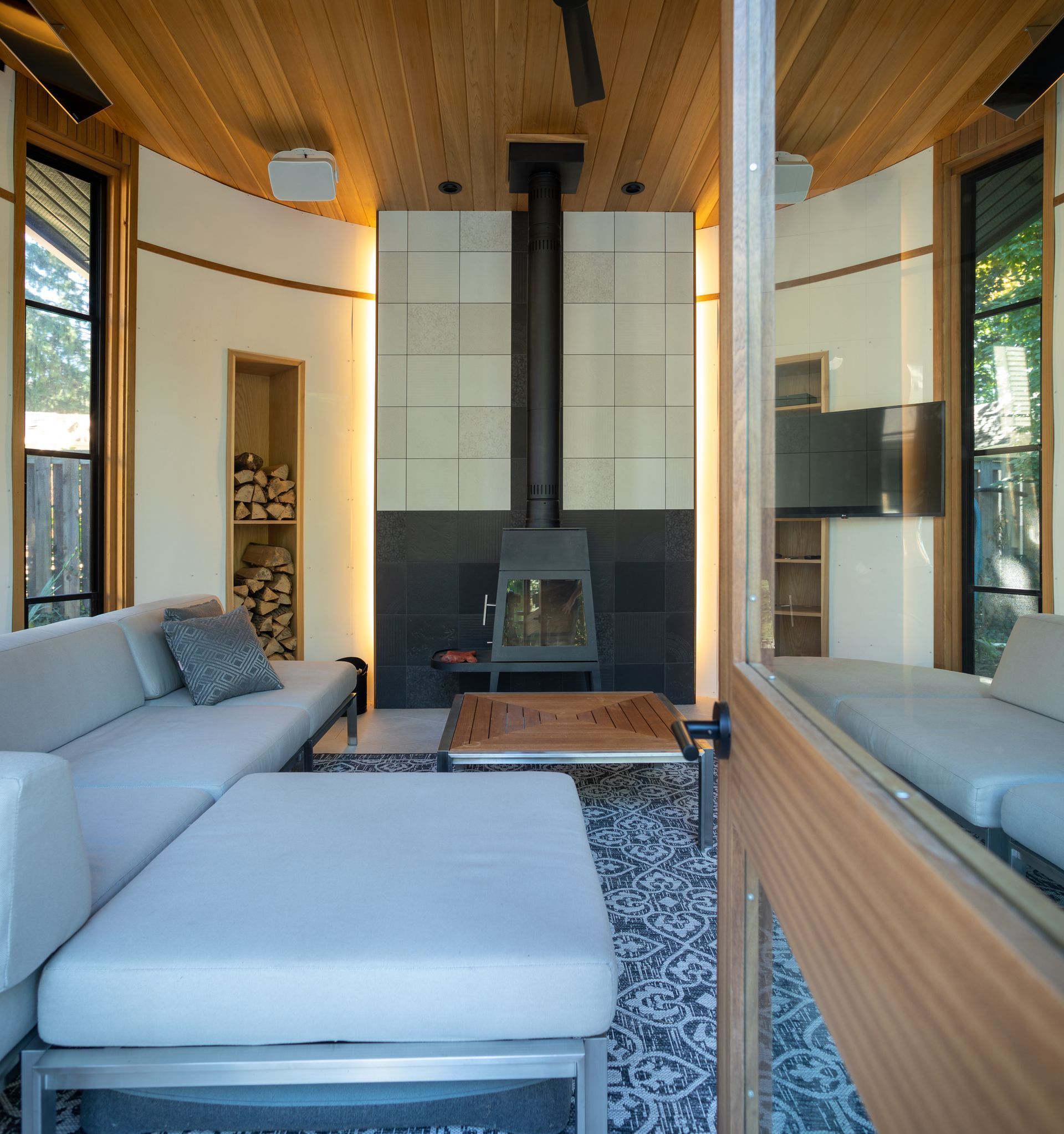 Cozy living room with a fireplace, light gray couch, and wood ceiling.