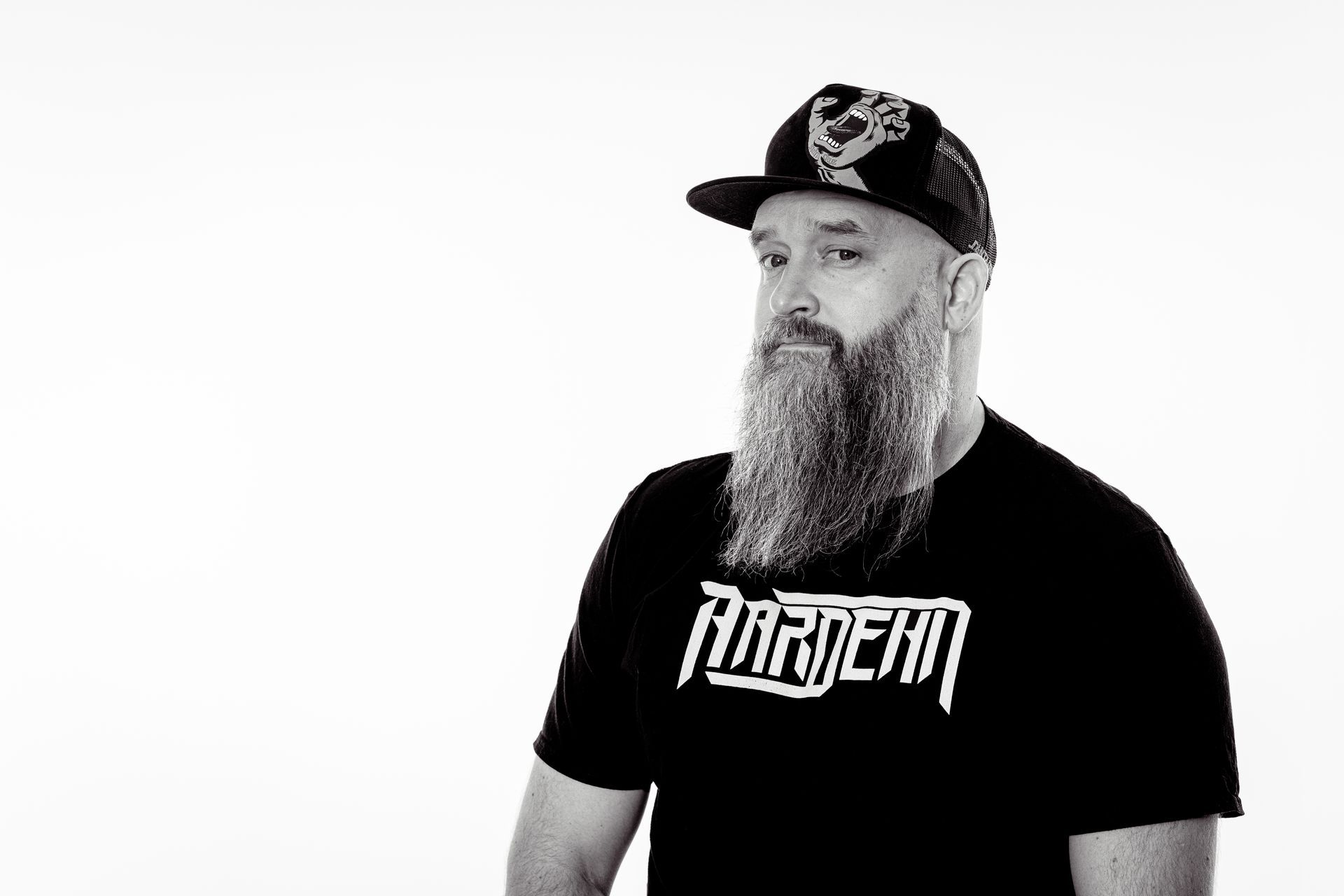 Man with long beard wearing a cap and black shirt with 