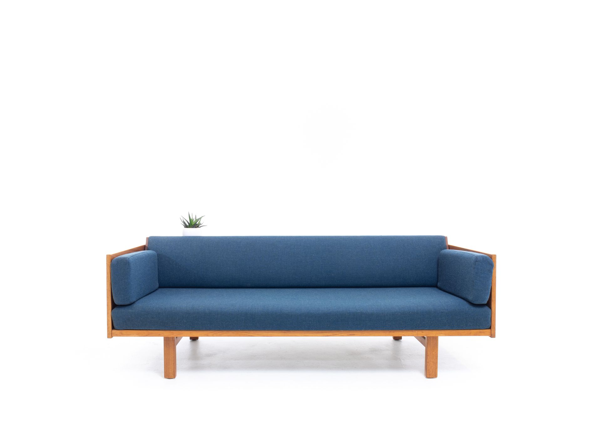 Blue upholstered sofa with wooden frame, on white background.