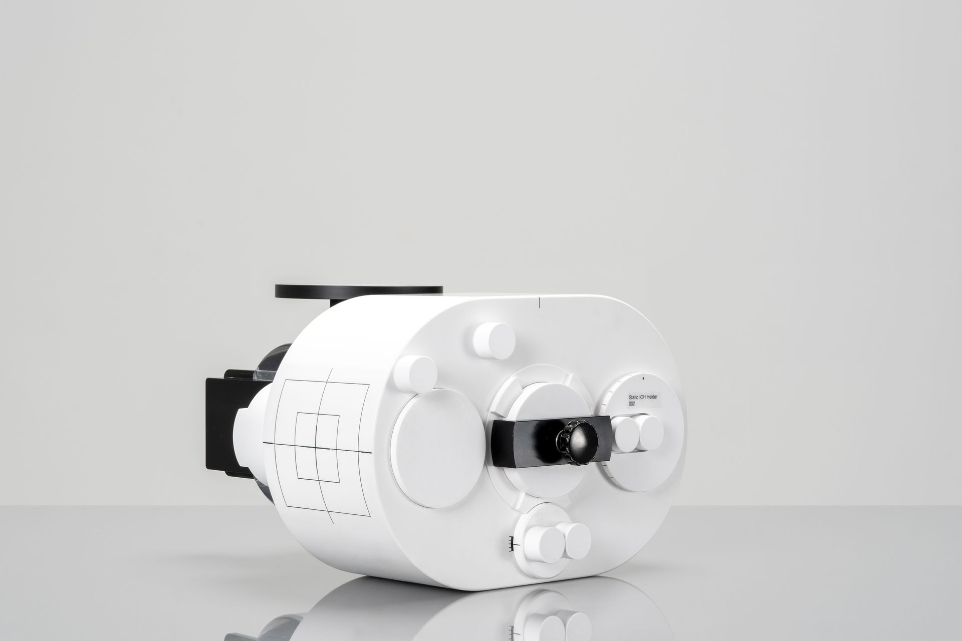 White cylindrical device with black attachments, possibly mechanical or technological.