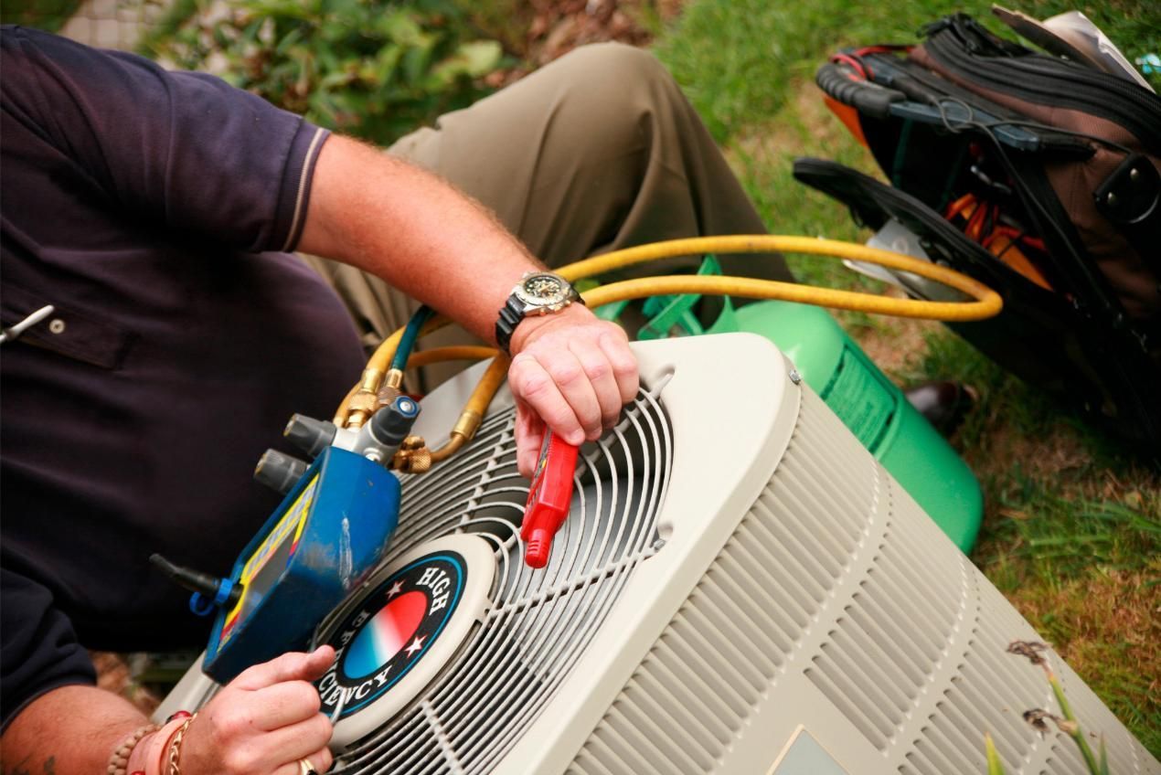 Technician checking outdoor air conditioner with gauges and hoses attached
