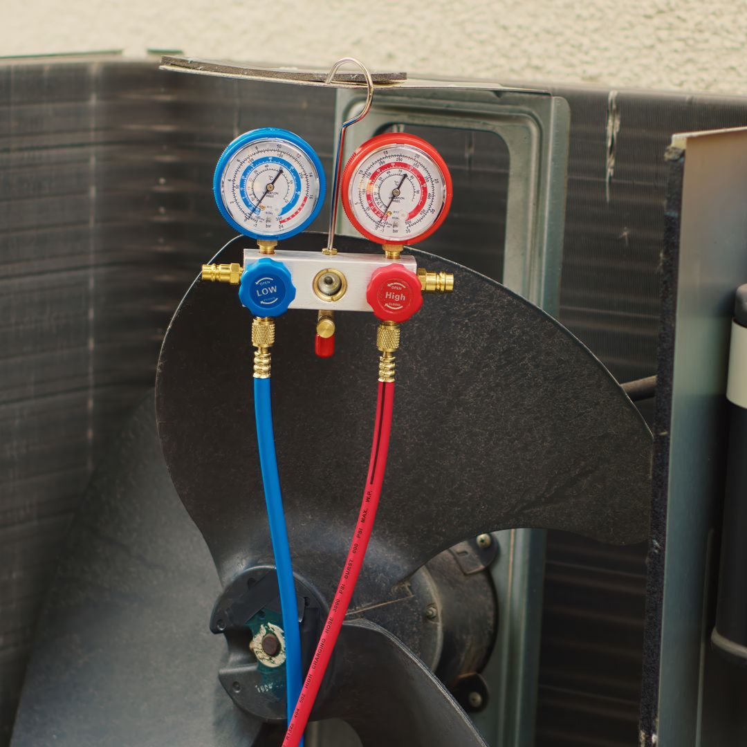 Blue and red pressure gauges attached to hoses on a black ventilation unit