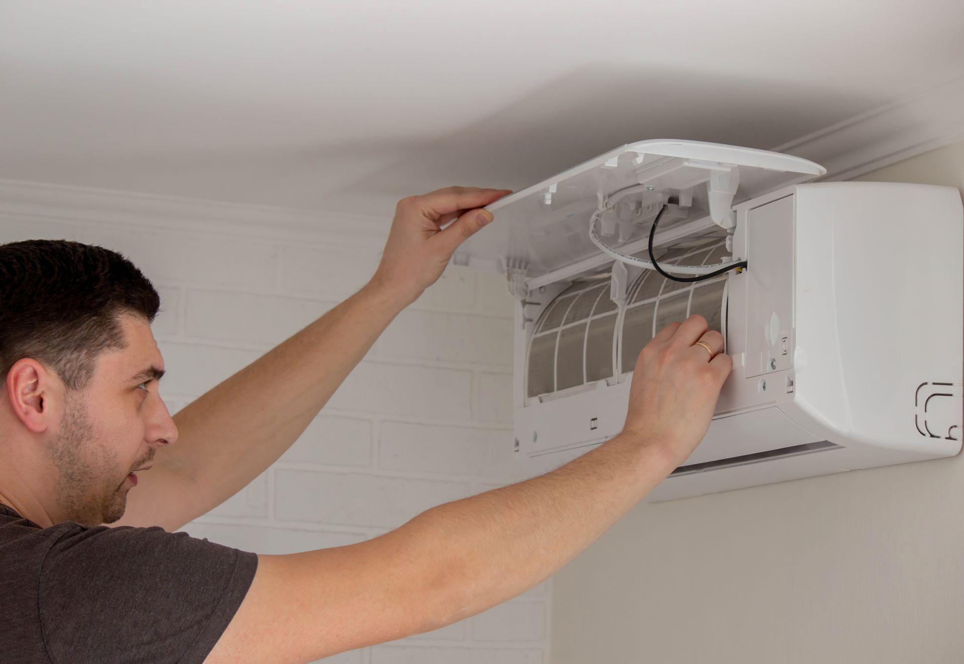 Technician repairing a wall-mounted air conditioner with the cover open