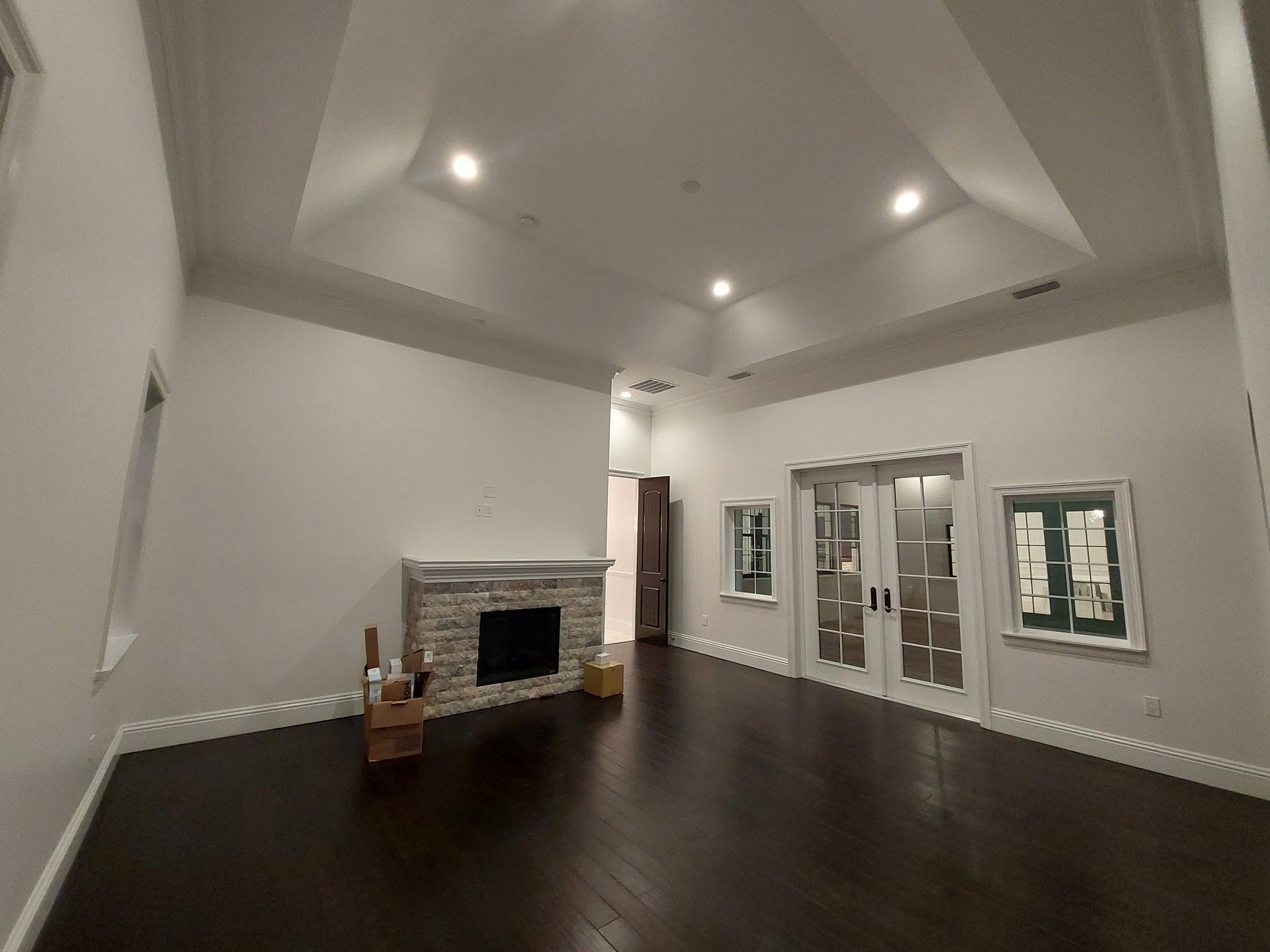 Empty living room with dark wood floors, white walls, a fireplace, and recessed ceiling lights