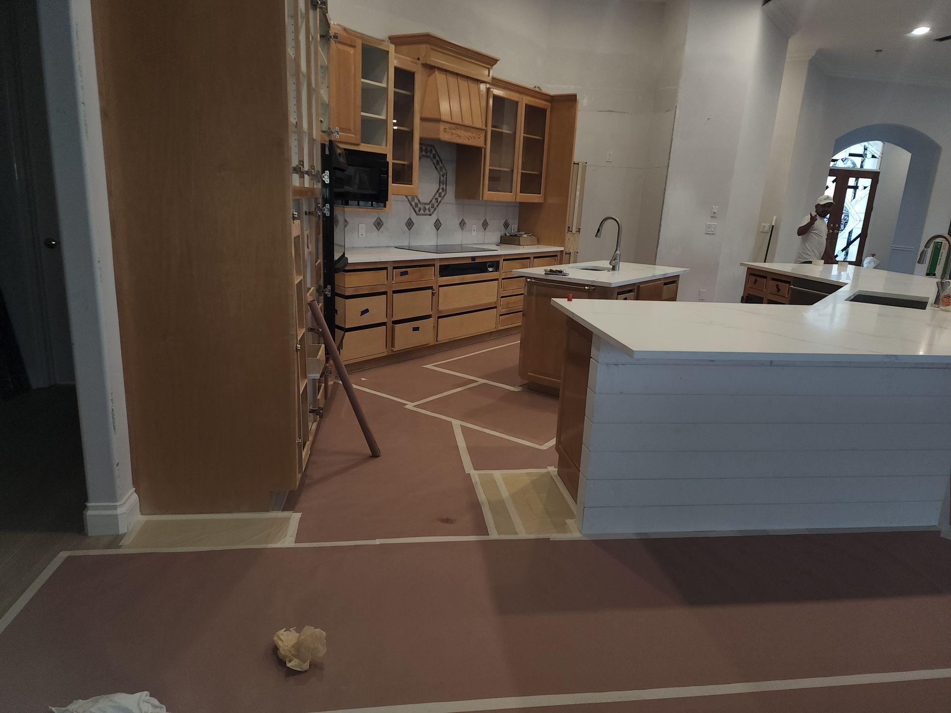 Kitchen under renovation with cabinets, island, and protective floor covering
