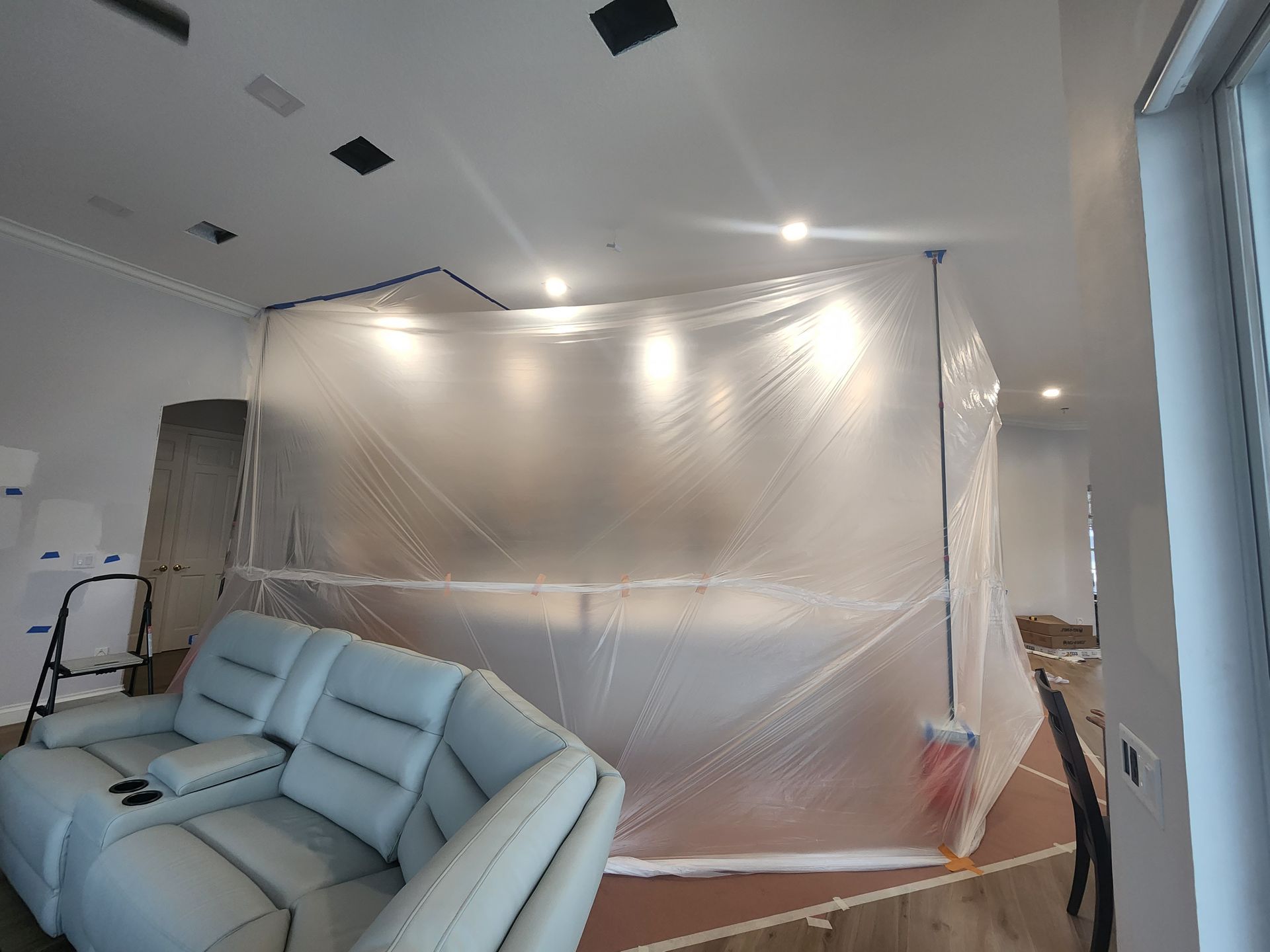 Living room with plastic sheeting covering walls and ceiling during renovation work Living room with plastic sheeting covering walls and ceiling during renovation work