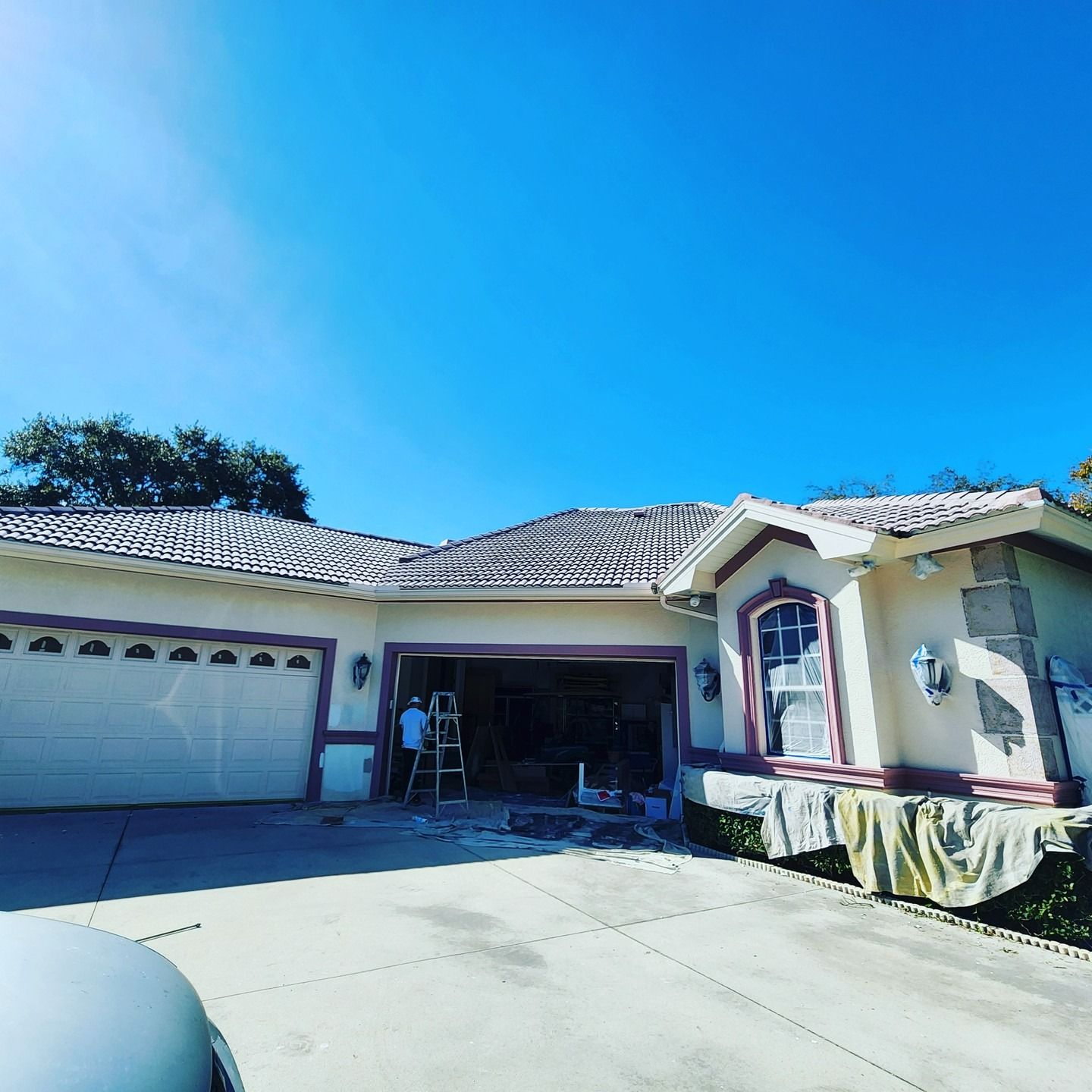 Single-story house with garage and open front entry under a bright blue sky, driveway in foreground