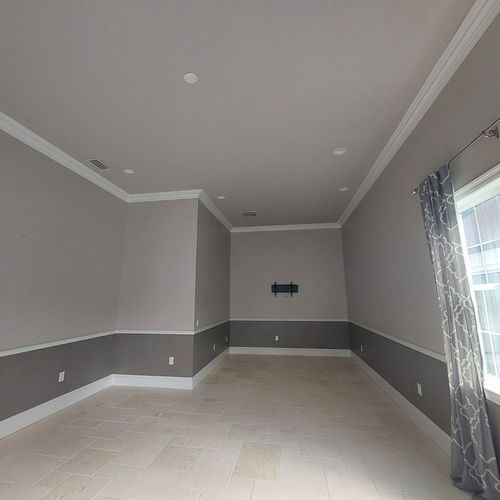 Empty modern room with gray walls, white trim, tile floor, recessed lights, and a window with curtains
