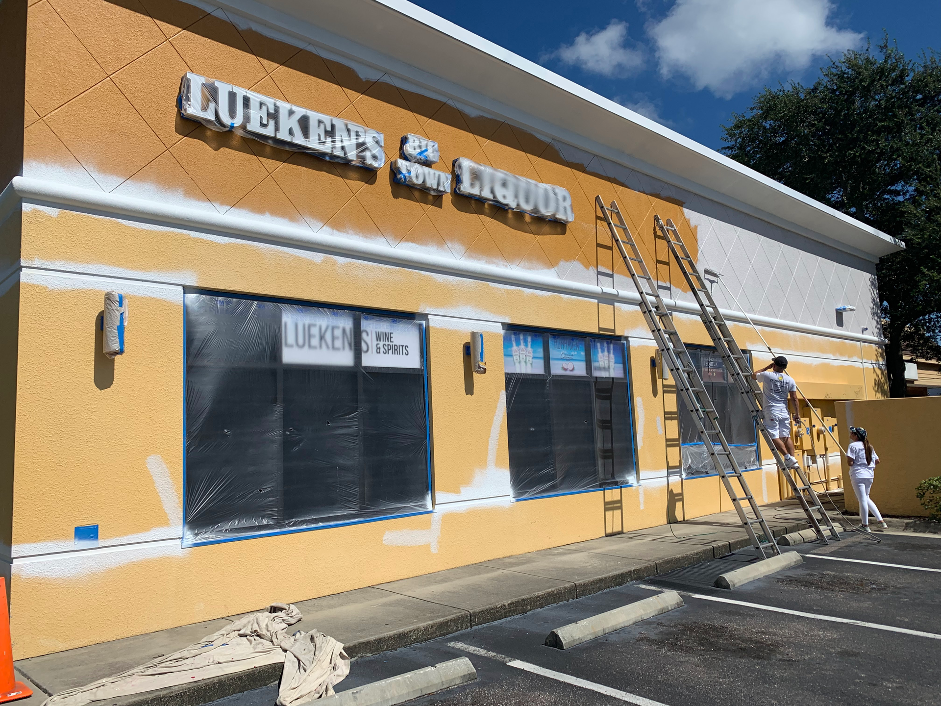Storefront of a school building with orange and white exterior, blue awning, and a ladder beside the entrance. Storefront of a school building with orange and white exterior, blue awning, and a ladder beside the entrance.