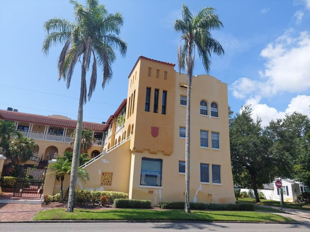 Yellow apartment building with palm trees and blue sky