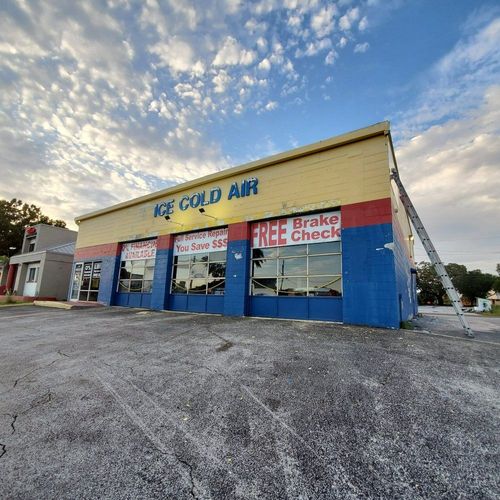 Auto repair shop exterior with blue-and-beige facade, red awnings, and sign for oil changes and brake checks
