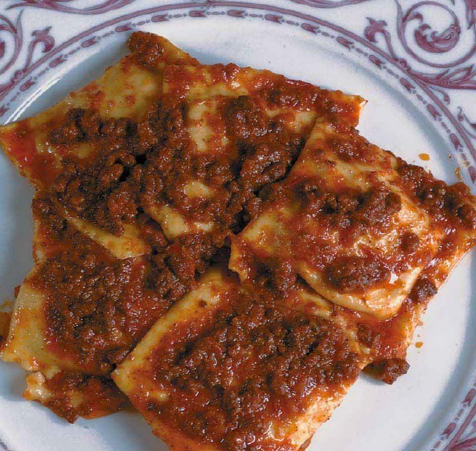 Piatto di ravioli conditi con una densa salsa di pomodoro e erbe aromatiche.