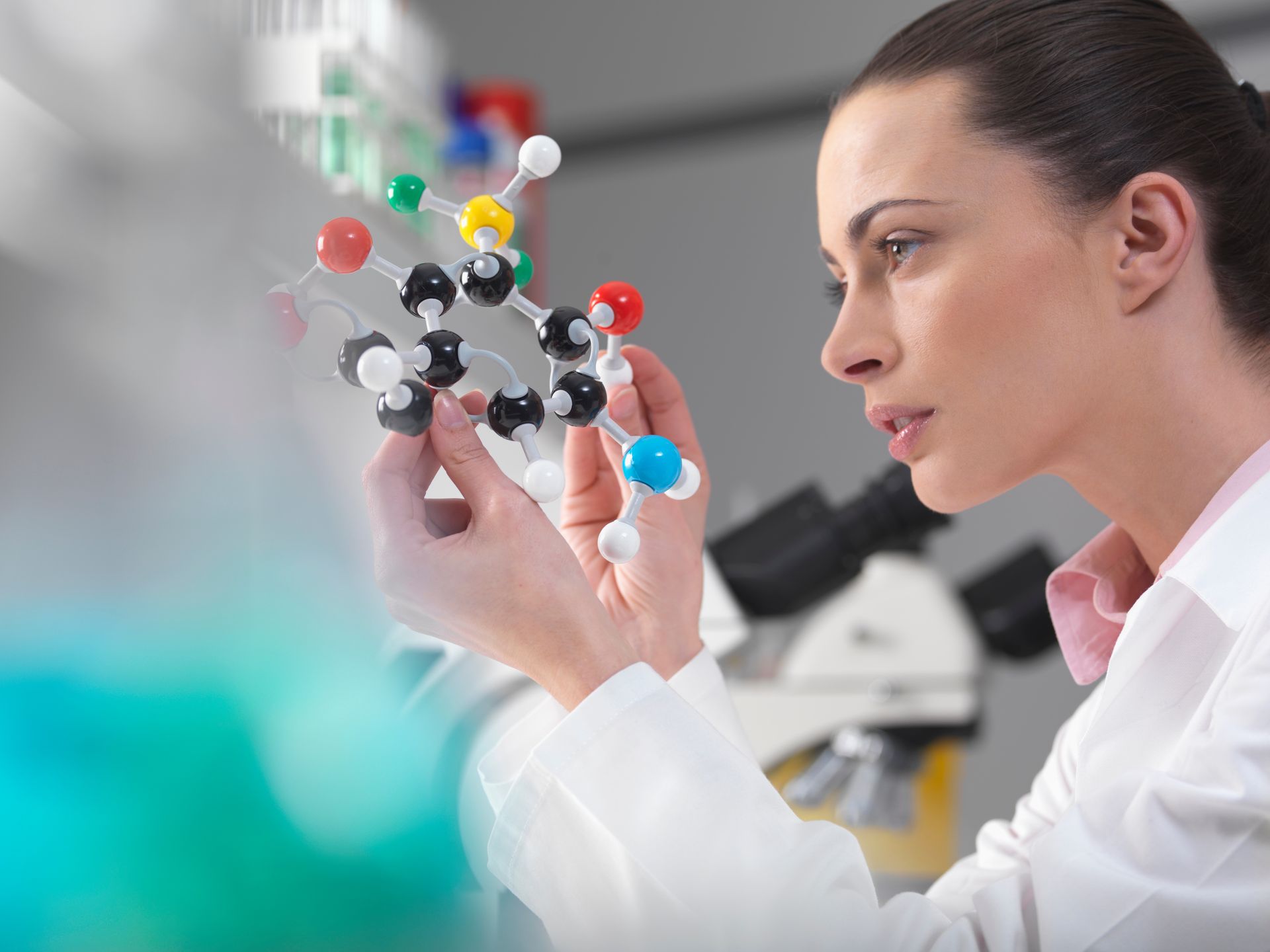 Una científica está mirando un modelo molecular frente a un microscopio.
