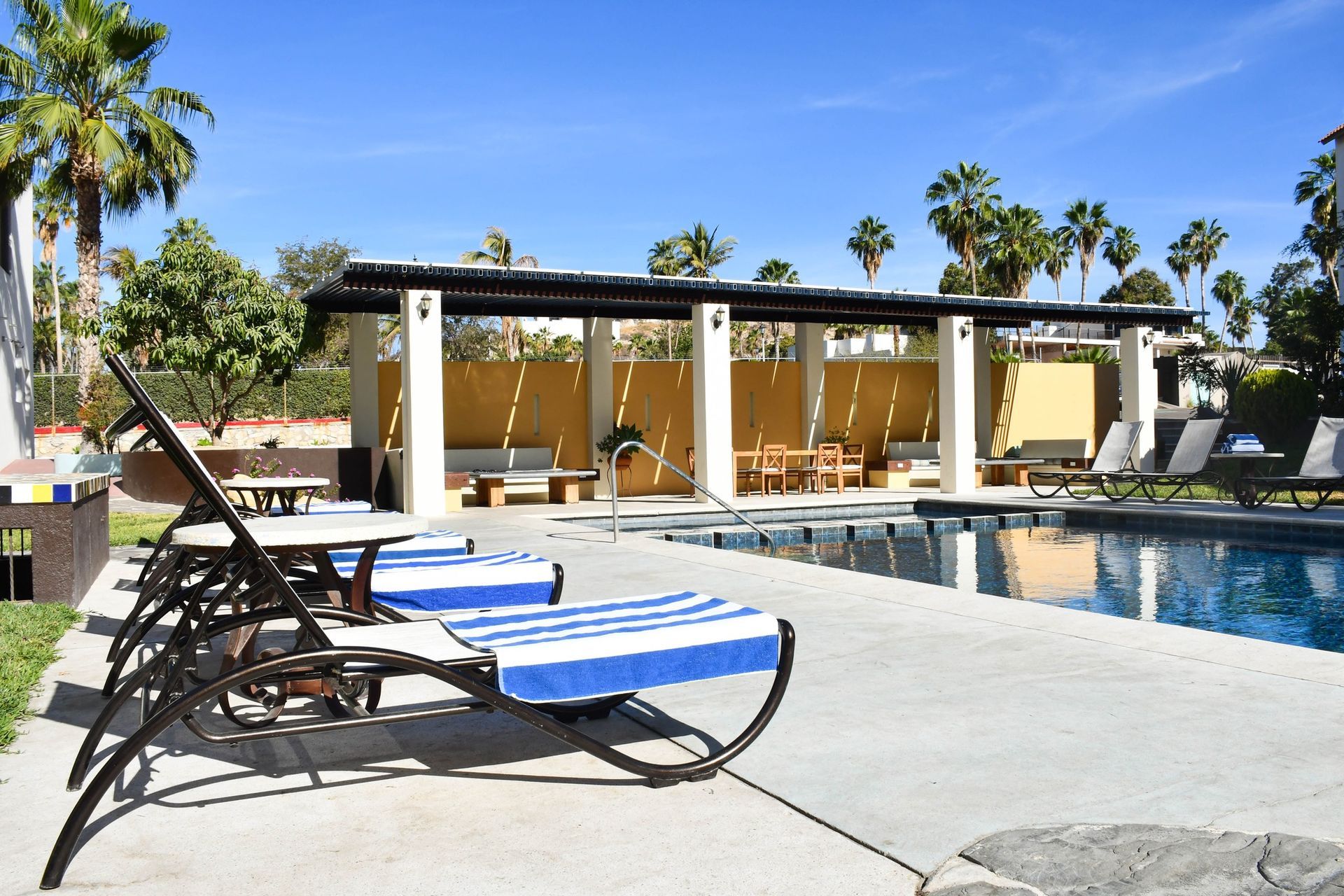 A swimming pool with blue and white lounge chairs in front of it