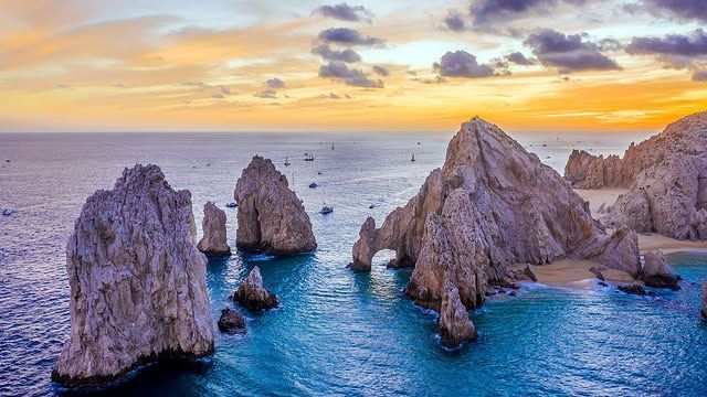 A group of rocks in the middle of the ocean at sunset.