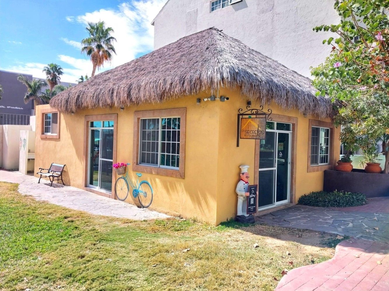 A yellow building with a thatched roof and a bicycle in front of it.