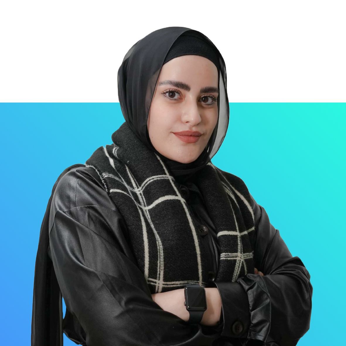 A woman wearing a hijab and a scarf is standing with her arms crossed.